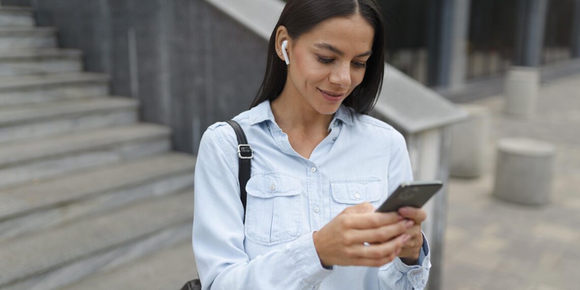 Mulher segura smartphone enquanto acessa informações sobre PIS PASEP