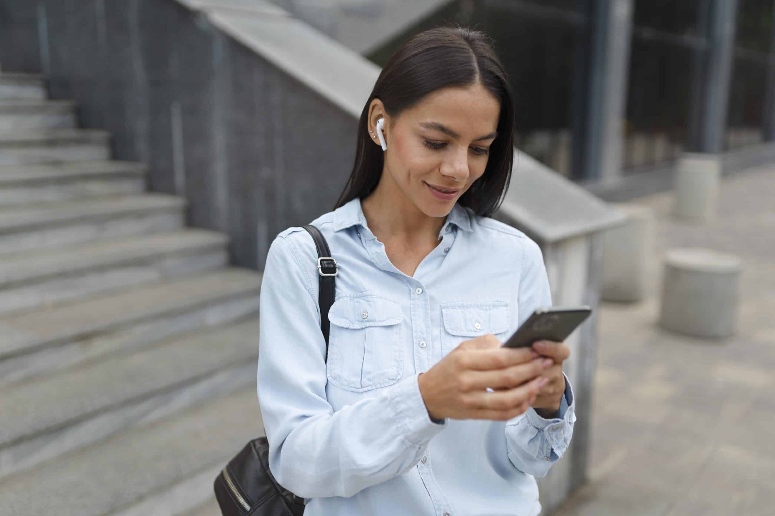 Mulher segura smartphone enquanto acessa informações do abono salarial