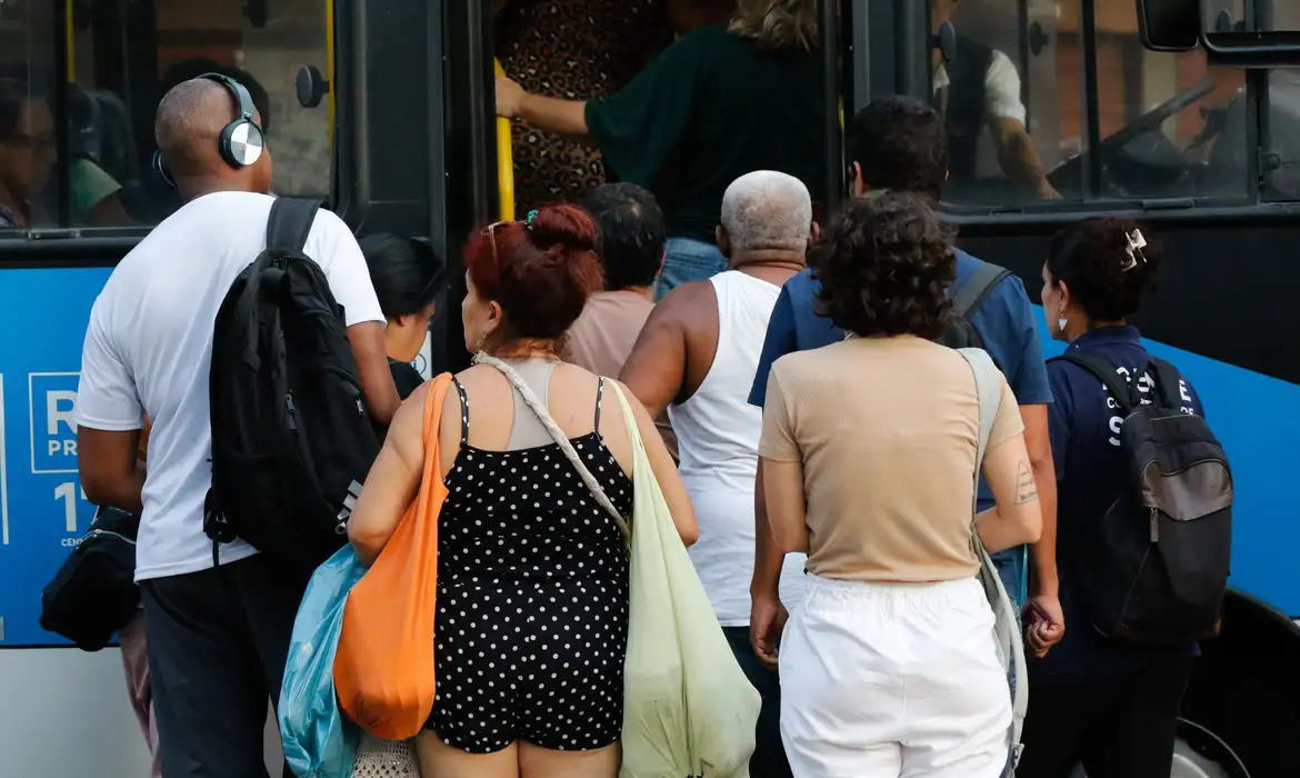 Fila de passageiros entrando em ônibus azul, aproveitando passagens gratuitas