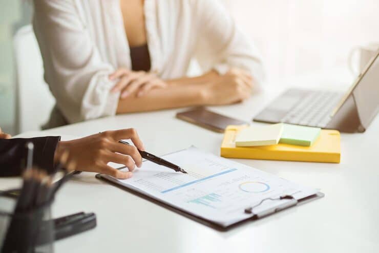 Mãos digitando no notebook ao lado e extrato bancário sobre mesa