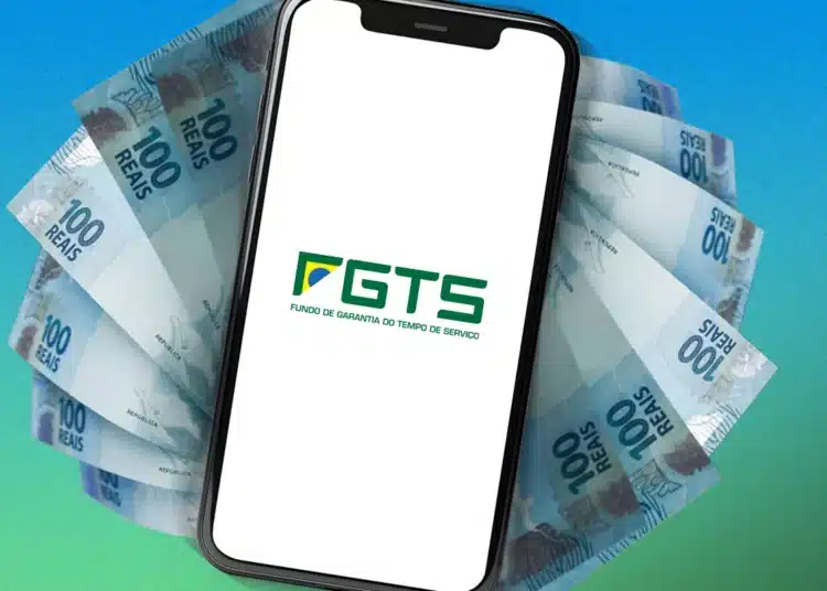 Celular exibindo logo do FGTS apoiado sobre notas de 100 reais em leque
