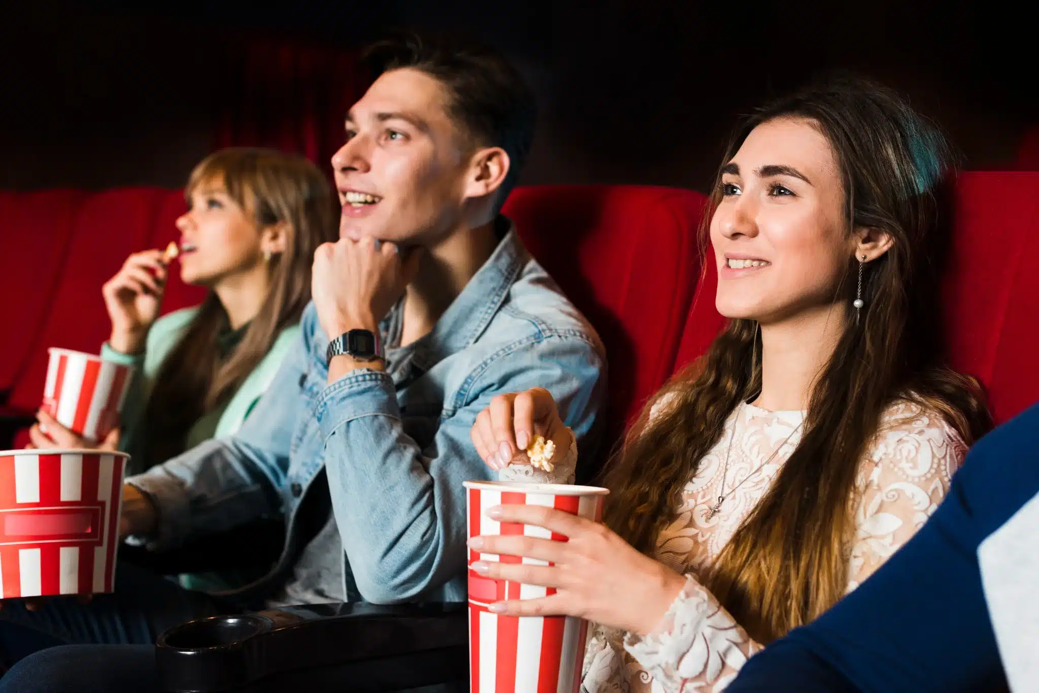 Grupo de pessoas assistindo a um filme no cinema com pipoca