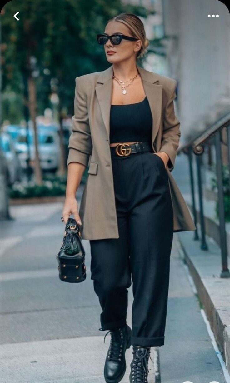 Close-up de calça preta de alfaiataria reta com a barra dobrada e coturno tratorado preto, em um look de rua elegante e moderno.