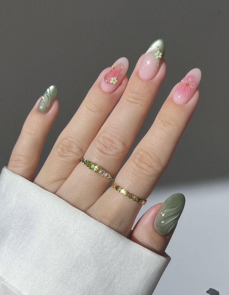 Mão feminina exibindo unhas no estilo Strawberry Matcha, alternando entre esmalte verde menta com textura ondulada e base nude rosada com pequenas flores delicadas em relevo e detalhes dourados.