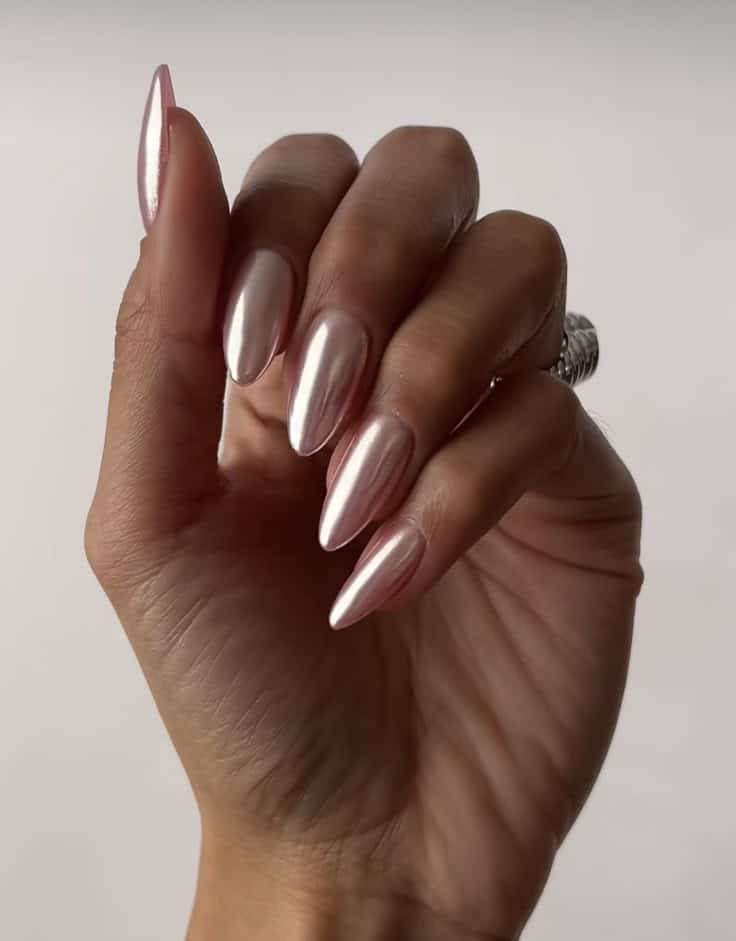 Close de unhas amendoadas com acabamento perolado e suave brilho espelhado (estilo glazed), refletindo a luz de forma delicada em um tom de branco leitoso.