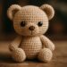 Urso amigurumi de crochê bege sentado sobre superfície de madeira com fundo escuro desfocado