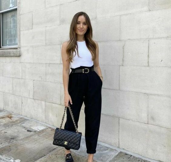 Mulher usando calça preta, blusa branca, mule preto e bolsa elegante na rua
