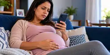 Mulher grávida em repouso no sofá consulta o celular, representando o pedido de auxílio-doença pelo Meu INSS.