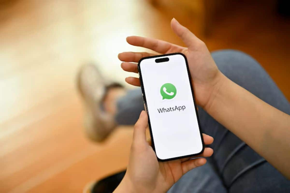 Mãos segurando celular com aplicativo do WhatsApp aberto na tela
