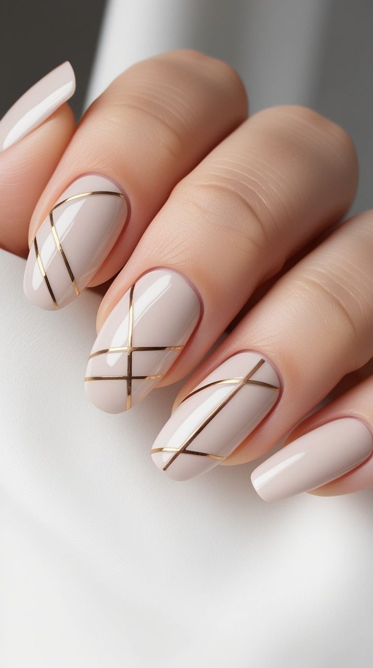 Unhas decoradas com linhas douradas geométricas sobre esmalte nude cintilante