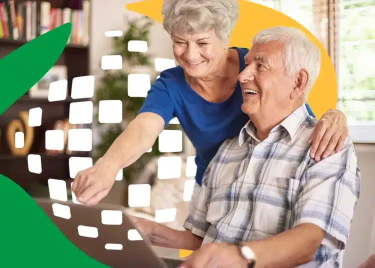 Um casal de idosos sorridentes, um homem sentado e uma mulher de pé ao seu lado, olhando para a tela de um notebook. A imagem possui elementos gráficos em verde e amarelo e pequenos quadrados brancos que sugerem conectividade digital.