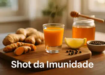 Copo pequeno com shot de imunidade, cúrcuma, limão, mel e pimenta sobre tábua