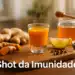 Copo pequeno com shot de imunidade, cúrcuma, limão, mel e pimenta sobre tábua