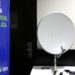 Uma antena parabólica digital branca montada sobre uma mesa, ao lado de um banner azul com a frase 'Prepare sua casa para a nova parabólica digital' e o logotipo Siga Antenado.