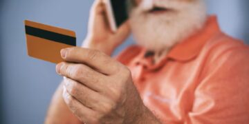 Idoso analisando cartão de crédito consignado recebido pelo correio