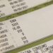 Close em uma conta de luz mostrando detalhes de leitura de consumo, medidor de kWh e descrição de taxas de iluminação pública e bandeiras tarifárias.