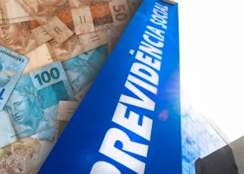 Notas de real ao fundo com fachada da Previdência Social do INSS