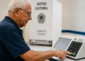 Idoso utilizando urna eletrônica durante as Eleições 2026 em seção de votação da Justiça Eleitoral.
