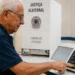 Idoso utilizando urna eletrônica durante as Eleições 2026 em seção de votação da Justiça Eleitoral.