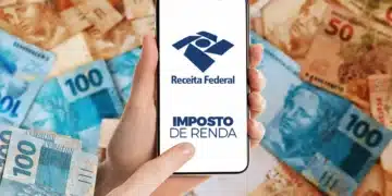 Celular exibindo Imposto de Renda da Receita Federal sobre notas de dinheiro representando restituição