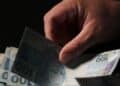 Mão manuseia cédulas de real durante o início dos pagamentos do INSS referentes a julho.