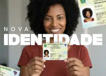 Close de uma mulher negra sorridente, com cabelo cacheado volumoso e vestindo uma blusa coral, segurando em primeiro plano a Nova Carteira de Identidade Nacional (CIN) em papel. O texto "NOVA IDENTIDADE" está sobreposto em destaque em letras brancas sobre ela. Outros exemplares do documento aparecem desfocados nos cantos superiores e inferiores, ilustrando o novo modelo.