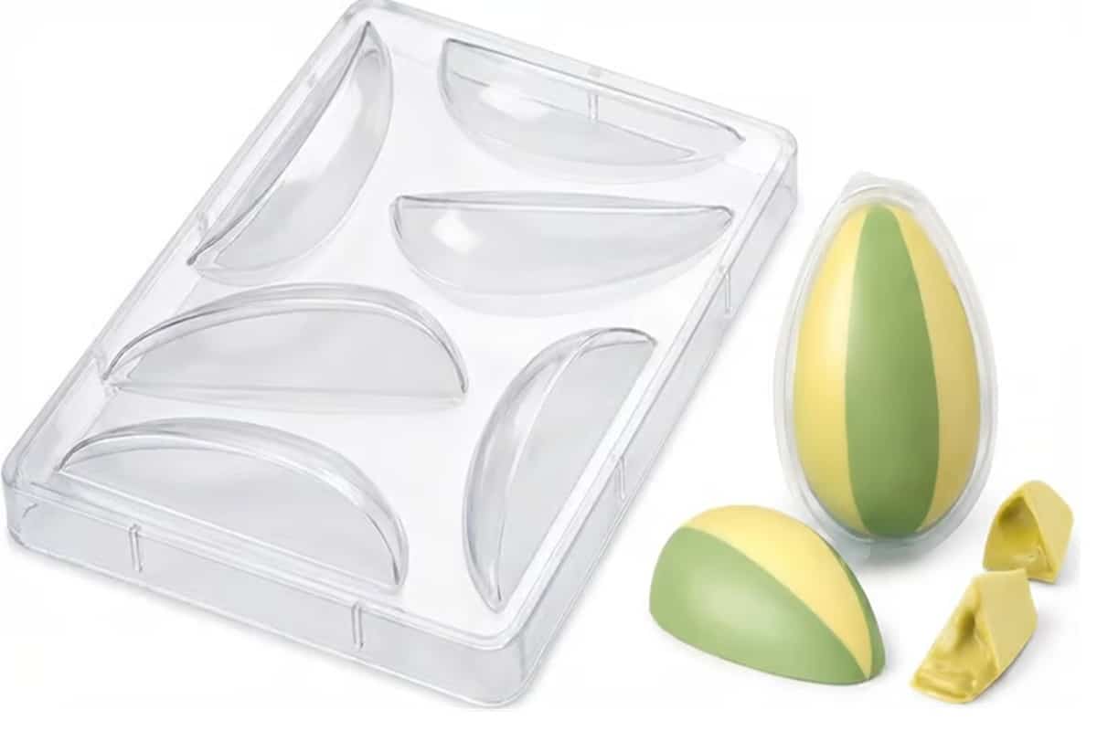 Forma de acetato transparente para ovo de Páscoa em fatias ao lado de ovos coloridos verde e amarelo montados e fatiados