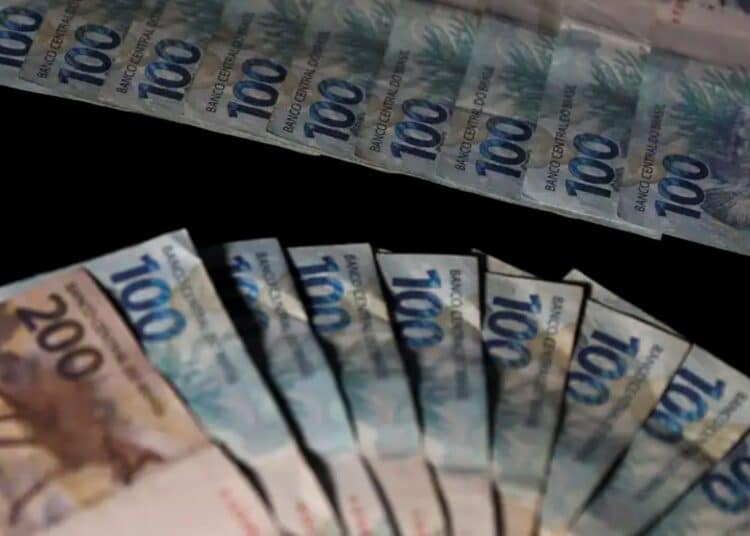 Leque de notas de cem e duzentos reais brasileiros sobre uma superfície escura, ilustrando o aumento do salário mínimo e benefícios previdenciários.