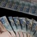 Leque de notas de cem e duzentos reais brasileiros sobre uma superfície escura, ilustrando o aumento do salário mínimo e benefícios previdenciários.