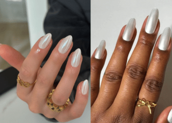Duas mãos femininas lado a lado: a da esquerda tem pele clara e anéis dourados, com unhas amendoadas pintadas de branco cintilante iridescente. A da direita tem pele negra e um anel de laço dourado, com unhas longas de branco cintilante opaco. Ambas sobre fundo neutro.