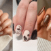 Colagem de três fotos apresentando variações da tendência unhas cappuccino. A primeira mostra um efeito marmorizado em tons de café com leite; a segunda foca em desenhos minimalistas de xícaras e grãos sobre fundo creme; a terceira exibe uma arte de luxo com latte art e filetes dourados em unhas amendoadas longas.