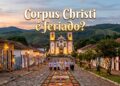 Sacerdotes caminham sobre tapete floral na rua de pedras, com Igreja Matriz de Santo Antônio ao fundo em Tiradentes, MG