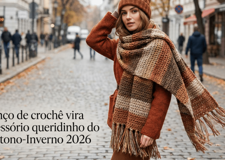 Mulher usa lenço de crochê xadrez em tons terrosos sobre casaco cor de cobre em rua de paralelepípedos no outono