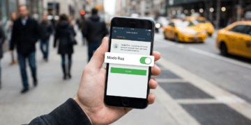 Mão segurando smartphone com app bancário mostrando botão Modo Rua ativado e botão verde Ativar, em rua movimentada com táxis