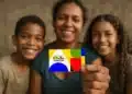 Mãe segura cartão colorido do Programa Bolsa Família ao lado de dois filhos, todos sorrindo