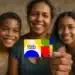 Mãe segura cartão colorido do Programa Bolsa Família ao lado de dois filhos, todos sorrindo