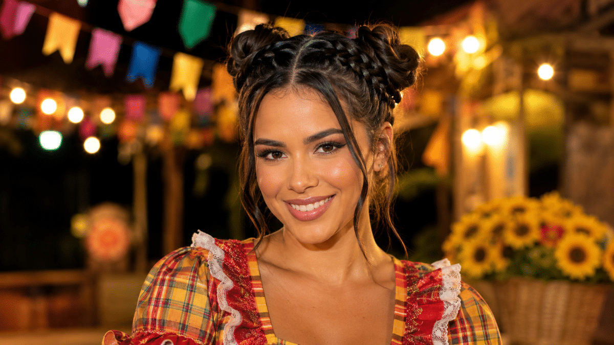 Jovem com vestido xadrez colorido e tranças em festa junina iluminada Mulher sorrindo com cabelo trançado, vestido xadrez, bandeirinhas e girassóis ao fundo