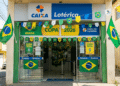 Fachada de lotérica CAIXA com bandeiras do Brasil, bandeirolas e cartazes Copa 2026 nas cores verde e amarela