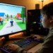 Menino de costas jogando Roblox em computador desktop com teclado mecânico RGB e monitor exibindo avatares coloridos