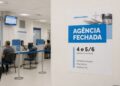 Cartaz de agência fechada no Corpus Christi em parede de sala de atendimento do INSS com guichês numerados ao fundo