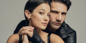 Kaan Urgancıoğlu e Pınar Deniz abraçados, ambos vestindo preto, em foto promocional da série Yargi: Segredos de Família