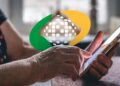 Mãos de idosa usando smartphone com logo do INSS sobreposto