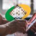 Mãos de idosa usando smartphone com logo do INSS sobreposto