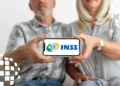 Casal idoso mostra tela de celular com logo do INSS, sentados juntos e sorrindo