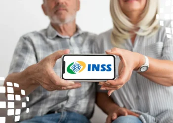 Casal idoso mostra tela de celular com logo do INSS, sentados juntos e sorrindo