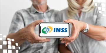 Casal idoso mostra tela de celular com logo do INSS, sentados juntos e sorrindo