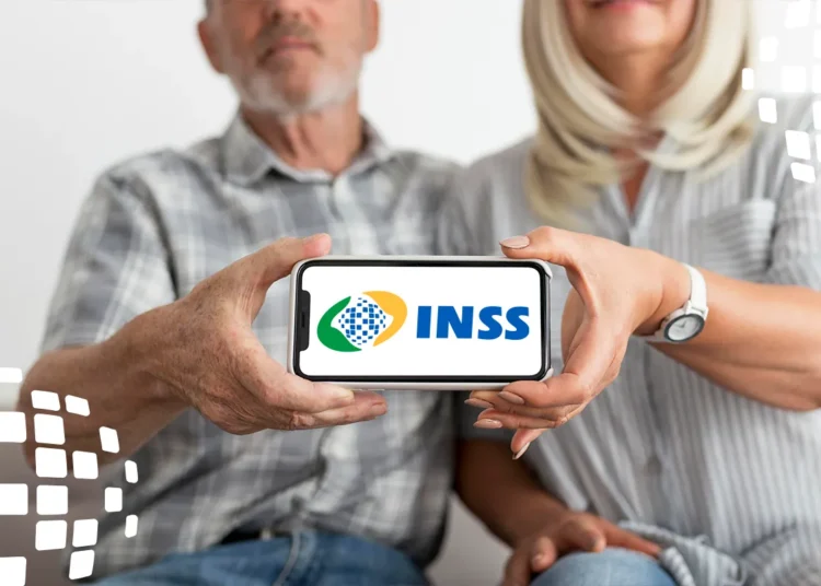 Casal idoso mostra tela de celular com logo do INSS, sentados juntos e sorrindo