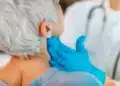 Profissional de saúde examina o pescoço de paciente durante atendimento relacionado à campanha Julho Verde.