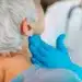 Profissional de saúde examina o pescoço de paciente durante atendimento relacionado à campanha Julho Verde.