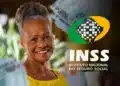 Mulher idosa sorridente segura notas de cem reais ao lado do logo do INSS